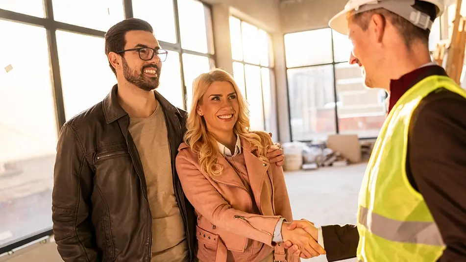 Builder shakes hands with smiling homeowners