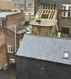 Photograph taken by member of the public of workers on roof with no fall protection measures in place