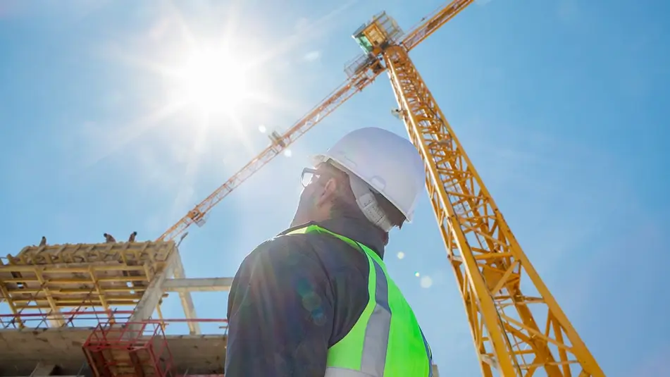 Construction worker looking up at sun in sky